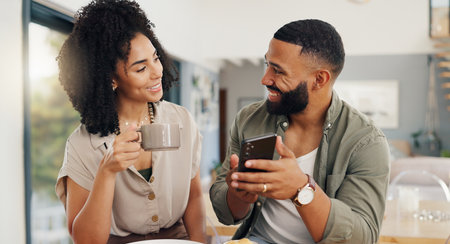 Couple, happy and coffee with smartphone for social media, sharing music or app explanation. Man, woman and technology in kitchen with breakfast for morning, relaxing and scrolling on online websiteの写真素材
