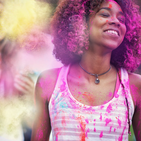 Powder, paint and woman at color festival in park, happiness and fun with celebration or party outdoor. Freedom, excited and colorful mess, smile with joy and culture, positivity and summer eventの写真素材