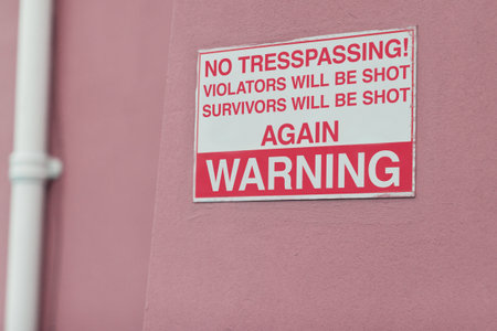 Comic, warning and sign on wall of property for caution, funny notification and information. Public signage, symbol and building with board, poster and joke for attention, security and safety messageの写真素材