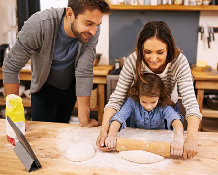 Family, cooking and learning in kitchen with tablet for recipe, guide and parents with child in home. Baking, mom and dad helping girl with rolling pin and talking about pizza, dinner or meal prepの写真素材