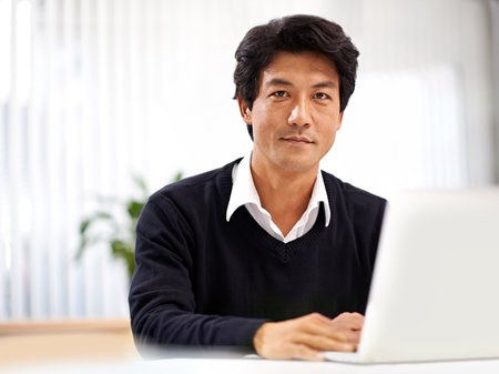 Advisor, laptop and portrait of asian businessman for schedule, communication or email in office. Professional, entrepreneur and Japanese employee with technology for internet, website and planningの写真素材