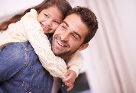 Happy, hug and piggyback for child from dad in home on holiday or relax with family on vacation. Father, love and support girl on back for funny game, bonding and playing together on weekendの写真素材