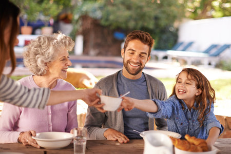 Happy family, food and breakfast in garden of home for nutrition, bonding and eating together with hosting. Parents, grandma and child with healthy diet, meal and relax at dining table in the morningの写真素材
