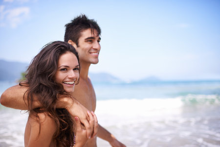Beach, smile and couple with vacation, travel and weekend break for honeymoon, summer and adventure. Romance, seaside and embrace with man and woman with holiday and love with anniversary and journeyの写真素材
