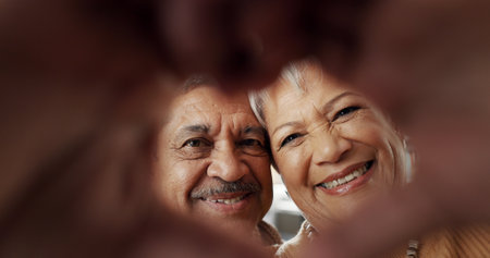 Happy, selfie and senior couple in a living room with heart, hands or frame zoom in their home together. Smile, portrait and elderly people bond in retirement with profile picture, memory or loveの写真素材