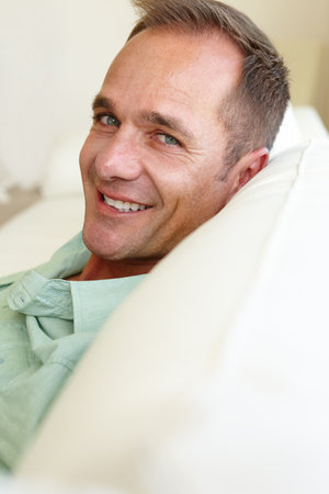 Portrait, guy or couch to relax at weekend in lazy, health or wellness as easy, self care or holiday. Tired, man or entrepreneur on sofa as happy, break or stress relief as rest and recreationの写真素材