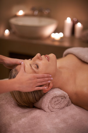 Face massage, spa and relax with woman, luxury and candle with hospitality and stress relief. Person, facial and girl with wellness or healthy with vacation or beauty with holiday, detox or self careの写真素材