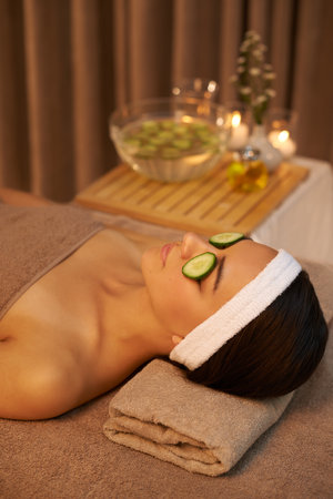 Skincare, relax and woman with cucumber on face for massage in spa for peace, calm or wellness. Facial, salon and person with vegetable on eyes in therapy, natural beauty or healthy organic treatmentの写真素材