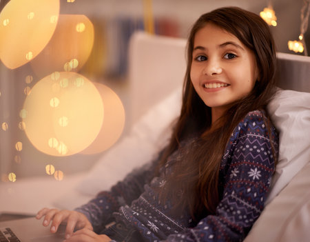 Portrait, night or kid with laptop for streaming, playing games and watching videos on a movie website. Smile, house or happy child with technology to download online or social media app to relaxの写真素材