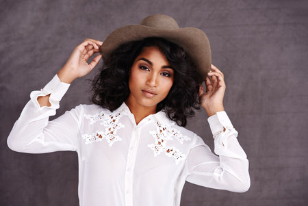 Portrait, studio and woman with cowboy fashion, confidence and relax with girl in stetson hat. Rodeo, western style and face Mexican model with cowgirl culture, wild west clothes and grey backgroundの写真素材