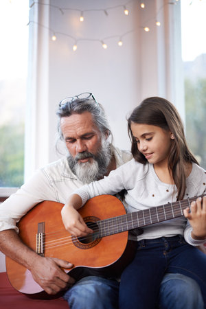Old man, girl or guitar as teaching, music or training as creative practice for skill development. Grandpa, kid or instrument as learning to mentor, guide or advice as song, bonding or togetherの写真素材