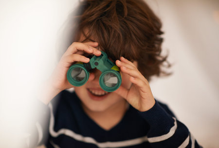 Boy, child and binocular with toys and playing, youth for fun and innocent with search or surveillance. Investigate, looking or curiosity with discovery on adventure, playful with games and activityの写真素材