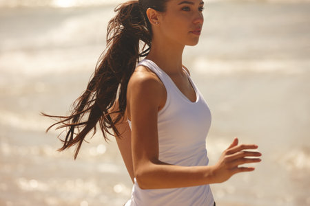 Woman, running and beach with fitness for workout, training or outdoor exercise in nature. Active and young female person or athlete enjoying run, cardio or physical activity on the ocean coastの写真素材