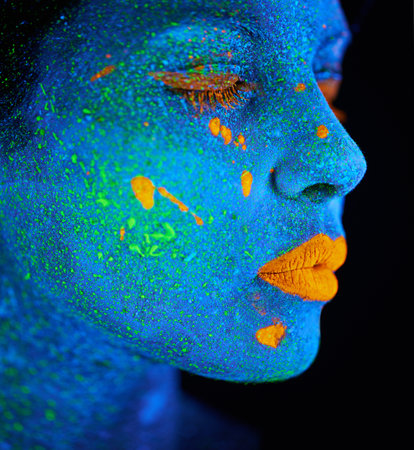 Woman, abstract and psychedelic paint for makeup with creativity, glow skin and fantasy beauty in studio. Girl, neon lips and cosmetics for portrait by black background, unique art and blue faceの写真素材
