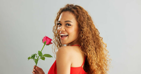 Woman, happy and rose in studio with smile for gift, kindness and gratitude with scent or fragrance on a white background. Face of excited, African person or model with pink flower for valentines dayの写真素材