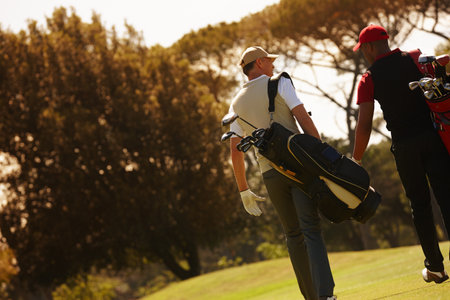 Men, golf course and walking for sports, game challenge and exercise for hobby in summer travel outdoor. Golfer or friends and talk with equipment for recreation and activity for fun on vacationの写真素材