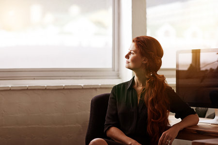 Businesswoman, thinking and office desk for future growth at tech startup for small business, entrepreneur or thoughts. Female person, contemplating and workplace vision for decision, planning or jobの写真素材