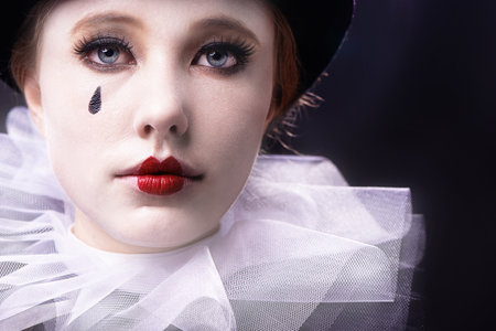 Face, woman and magician performer in studio on black background with creative makeup for entertainment, artist and passion. Portrait, female person and outfit to perform tricks or jokes at circusの写真素材