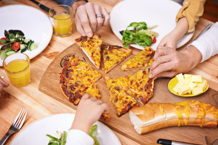 Hands, pizza and top view of family eating food at table in home for lunch or hungry for bread. Margherita, group and people with mozzarella slice for dinner with salad on plate, cheese and closeupの写真素材