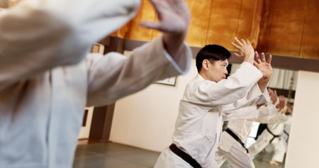 Aikido class, group and people for martial arts, strike or together for combat at training, gym or dojo. Black belt students, fight and exercise for workout, fitness and conflict at Japanese clubの写真素材