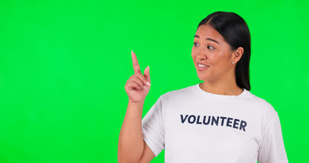 Volunteer, green screen and a woman pointing at space for advertising, charity or information. Face...