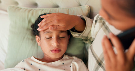 Sick girl, fever and phone call with a mom talking to a doctor to make an appointment for her daughter. Kids, family and a female child in bed with a mother speaking to a gp about healthcare at homeの写真素材