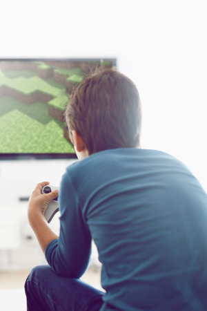Video, game and boy in home playing with internet connection, weekend and challenge from back....