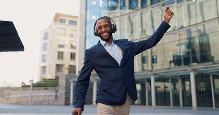 Business man, dancing and headphones in city with smile, steps and spin with bag for commute by office buildings. Person, employee or excited dancer with music, briefcase or outdoor on metro sidewalkの写真素材