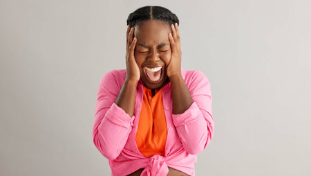 Anxiety, screaming and hands on face of black woman in studio with mental health crisis on grey...