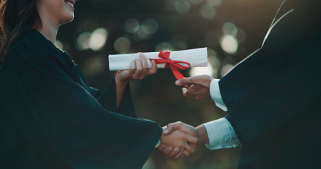Hands of people, giving and certificate for graduation on campus, achievement and success with degree. College, graduate or handshake with diploma in education, celebration or ceremony in universityの写真素材