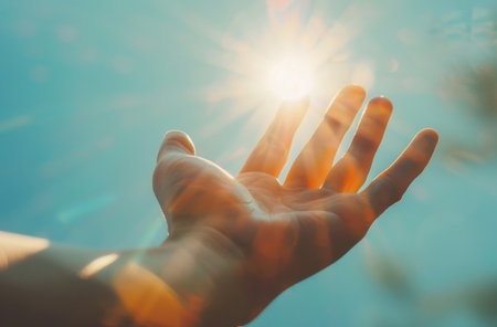 Faith, reach and hand in sunshine on blue sky for religion, hope and inspiration for spiritualの素材