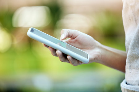 Person, hand typing and mobile phone in park for social media, communication or networking outdoors....