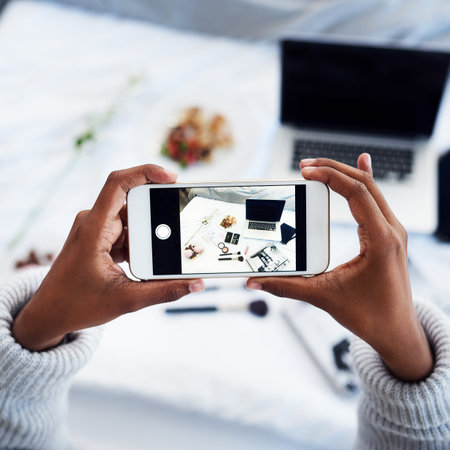 Person, hands and cellphone screen with photography in home as content creator, beauty or influencer. Smartphone, makeup and bedroom for online communication or small business, top view or laptopの写真素材