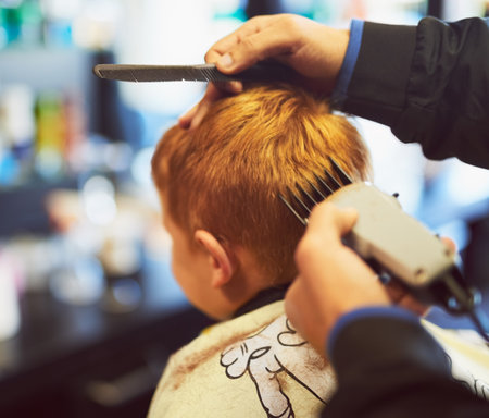 Young, boy and barber haircut or clippers for grooming style in salon, childhood or development. Back, hands and electric shaver for cleaning hygiene with new look or customer service, youth or trustの写真素材