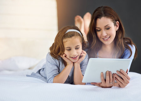 Relax, tablet and mom with child on bed at home watch online video on app, internet or social media. Smile, love and mother with girl streaming movie, film or show on digital technology in bedroom.の写真素材