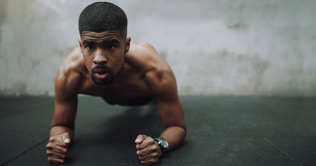 African man, plank and floor in gym for fitness, health and strong core muscle with vision in training. Person, exercise and intense workout for wellness with stretching for abdomen, stomach or absの写真素材