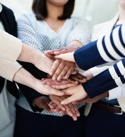 Office, teamwork and group of people with hands together in huddle in solidarity, creative collaboration or support. Synergy, employee engagement or professional women in growth, development or trustの写真素材