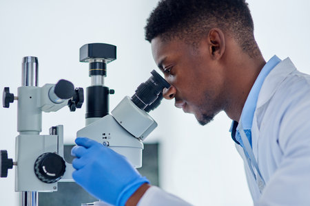 Science, research and black man with microscope for analysis, investigation or medical engineering in laboratory. Biotech, lab technician or scientist checking vaccine sample for pharmaceutical test.の写真素材
