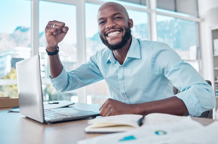 Black man, laptop and celebrate in office portrait, online success and prize giveaway or bonus. Male person, excited and fist pump for victory in workplace, lottery and promotion or reward on websiteの写真素材