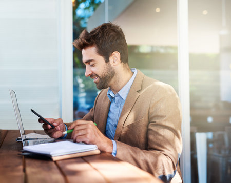 Phone, smile and businessman with laptop in coffee shop working on freelance budget plan with research. Technology, cellphone and financial advisor reading email with computer in cafe or restaurant.の写真素材