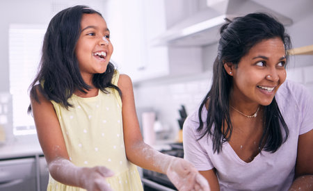 Girl, mother and play with flour or laugh in kitchen, baking and fun with ingredients in home. Daughter, mommy and bonding or Indian family for cookies preparation, childhood and learning pastryの写真素材