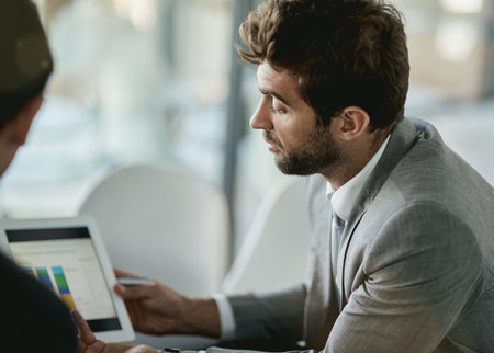 Business, men and office with graphs on tablet for performance or financial analysis and investment review. Male employees, communication and digital technology for online infographic and statistics.の写真素材