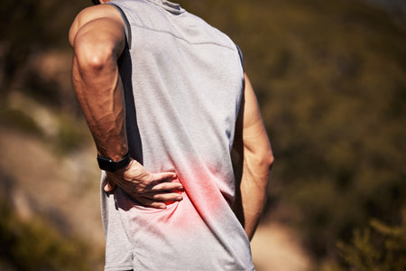 Man, runner and back pain in nature, injury and hurt outdoors on exercise or workout and accident. Male person, inflammation and fibromyalgia or sciatica issue, spine and strain while hiking or walkの写真素材