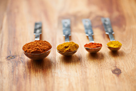 Spoons, spice and collection of powder for seasoning on kitchen table, turmeric and paprika for meal. Digestion, condiments and options for cooking in Indian culture, weight loss and food preparationの写真素材