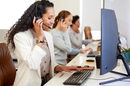 Agent, woman and headset with smile on computer for call center or customer care in office with coworkers. Female person, technology and operator for telecommunication, company and workplace or jobの写真素材