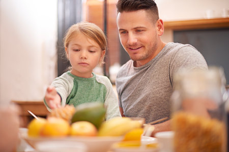 Family, father and kid eating breakfast in home together for healthy diet, nutrition or wellness in the morning for development. Food, parent and happy dad with girl at table with fruits for growthの写真素材