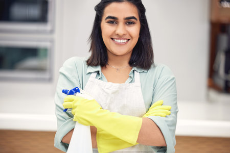 Cleaner, portrait and smile with gloves or confidence in house for cleaning, scrub and dirt on furniture. Indian woman, happy and housekeeping with detergent in bottle for dust in home or living roomの写真素材