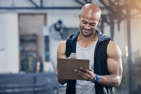 Man, clipboard and sports coach in gym with writing notes for client appointment, strong body and fitness. Personal trainer person, paperwork and admin in wellness club for business and training jobの写真素材
