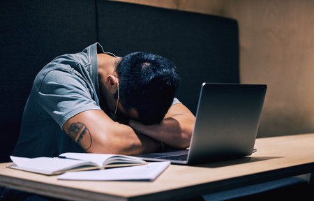 Remote work, burnout and businessman sleep at cafe with laptop, book or 404 anxiety, glitch or connection fail. Night, restaurant and freelance writer with deadline anxiety, fatigue or article stressの写真素材