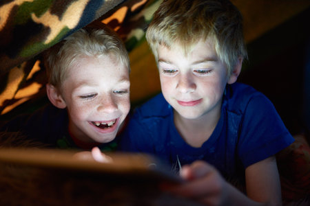 Smile, kids and brothers on tablet in tent at home for game, movie or streaming cartoon online at night together. Happy children, siblings and technology for app, internet or family relax in houseの写真素材